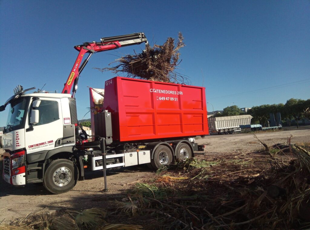 Camión grúa con pulpo cargando podas